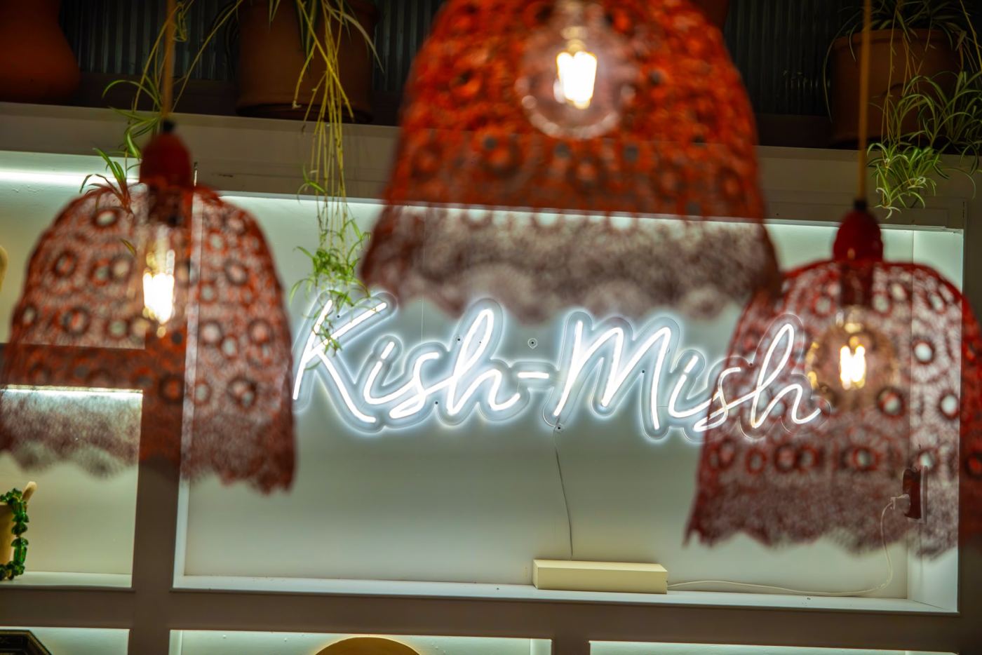 The glowing Kish-Mish neon sign between lace lanterns