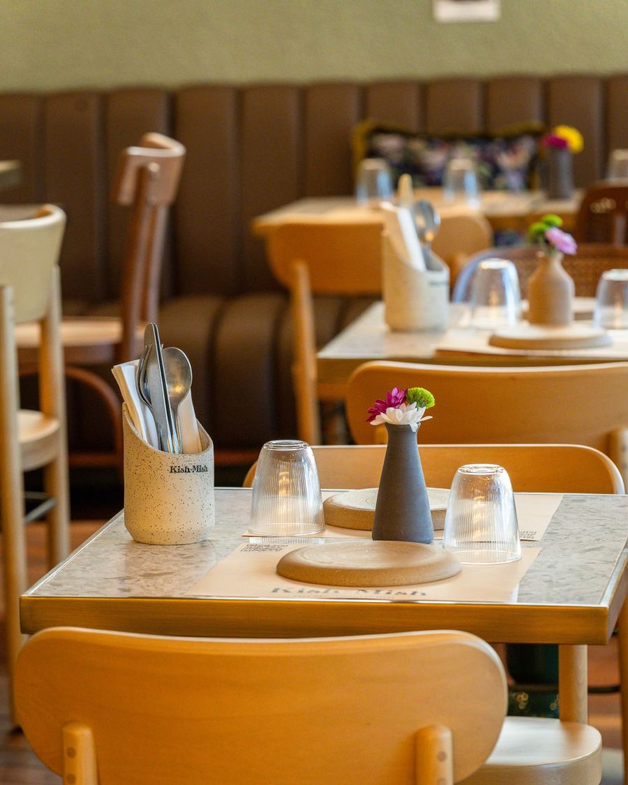 A table set with a small vase of flowers and cutlery