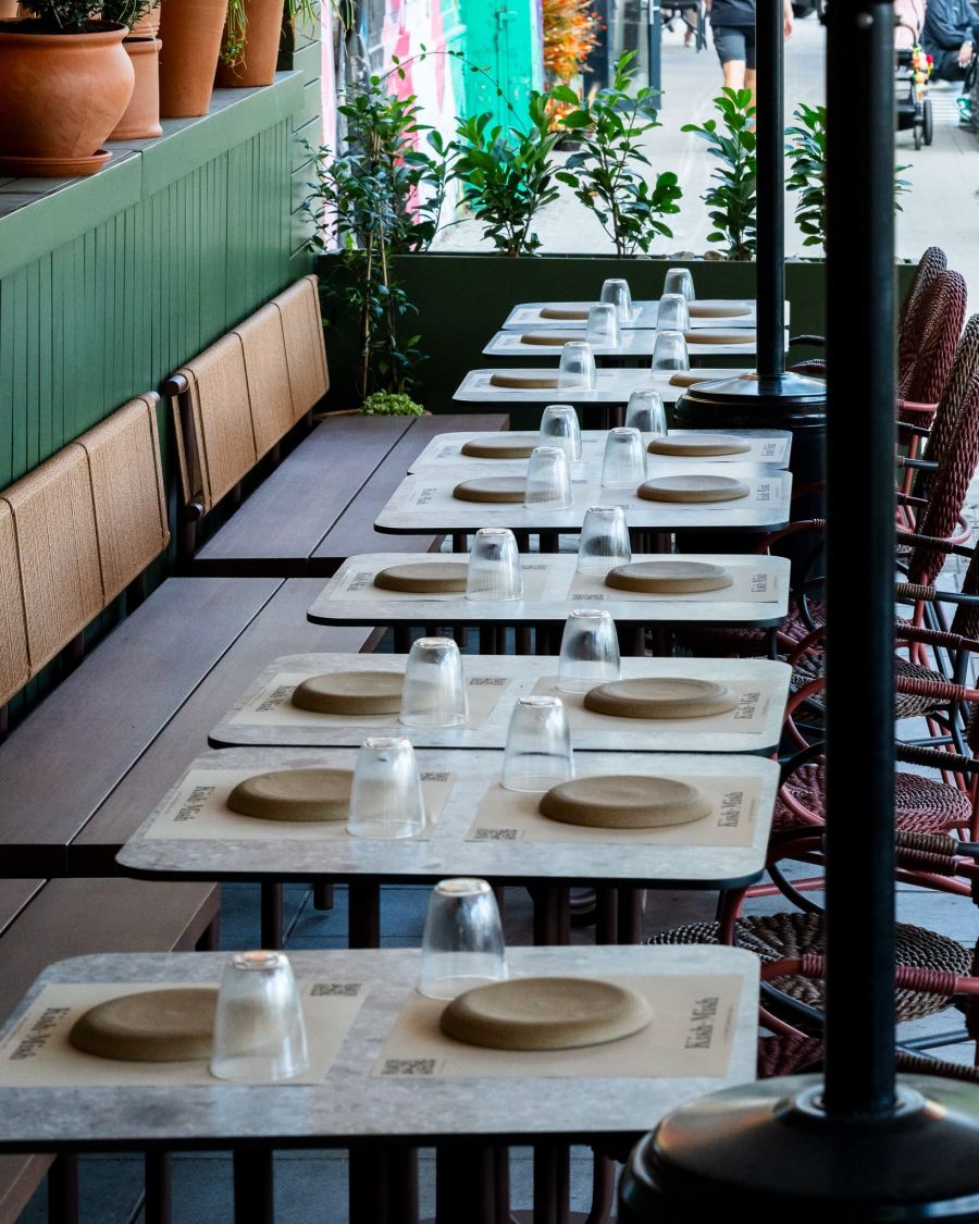A long row of terrace tables laid with plates and glasses