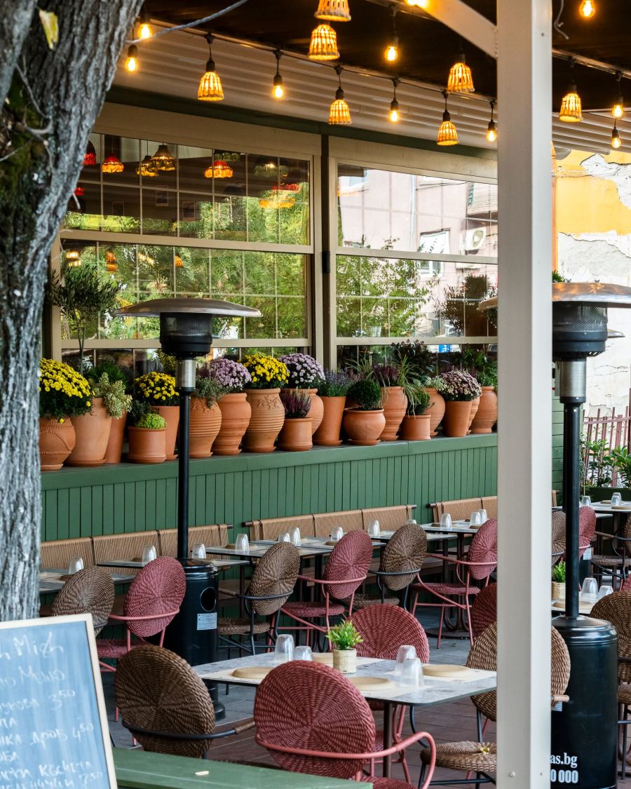The terrace at dusk under strings of lanterns and potted flowers