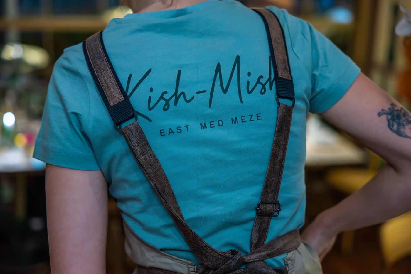 A Kish-Mish server in her apron and teal T-shirt